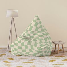 a green and white checkered bean bag chair next to a small table with a lamp on it