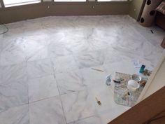 a room with white marble flooring and paint on the ground next to a window