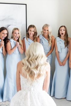 a bride and her bridesmaids laughing in front of a mirror