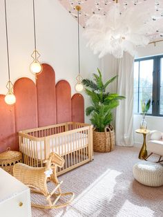 a baby's room is decorated in pink and gold with hanging lights above the crib