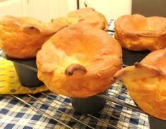 several muffins sitting on top of black trays with blue and white checkered table cloth