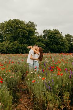 a man and woman kissing in a field full of flowers