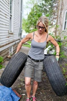 a woman holding two large tires in her hands