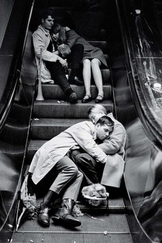 two people are sitting on an escalator and one person is hugging the other