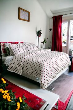 a bed room with two beds covered in white and red polka dot sheets next to a window