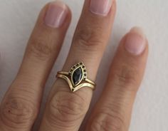 a woman's hand wearing a gold ring with a black stone in the middle