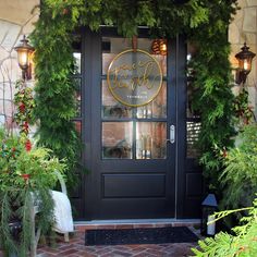 a black door with gold lettering and greenery on the front entrance to a restaurant