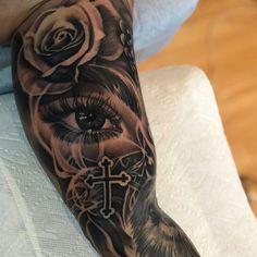 a woman's arm with a cross and roses on it, in black and grey