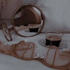 a cup of coffee sitting on top of a bed next to a mirror