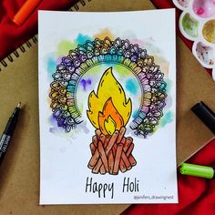 a happy holi greeting card with watercolors and crayons on the table