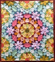 a multicolored quilt with an intricate circular design on it's center piece