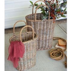 two wicker baskets sitting on the ground next to rope and flower potted plant