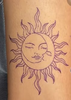 a sun tattoo on the side of a woman's leg with her eyes closed