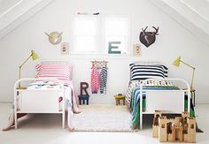 an attic bedroom with two beds and white walls