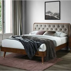 a bed sitting in a bedroom on top of a wooden floor next to a window