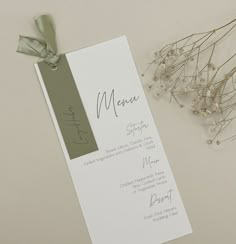 the menu card has been placed next to some dried flowers and a green ribbon on it