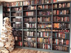 a large bookcase filled with lots of books next to a wooden floor and wall