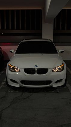 a white car parked in a parking lot next to two other cars at night time