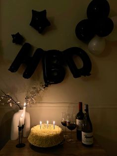 a birthday cake with candles and wine on a table