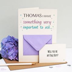 there is a purple envelope and two cards on the table next to some blue flowers