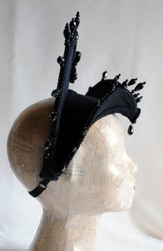 The Queen of Darkness headdress is a glorious Tudor inspired attifet headdress with a gothic twist!This vampire style headdress is covered with black silk shantung and embellished with black cord trimming all around the edges.It is further trimmed with black crystal details that create a halo effect. The piece is completed with a black crystal handmade elements placed at the center of both at the frond as well as the back part,to add that extra drama that we all love! The base is a headband styl Black Medieval Costume Accessories For Costume Party, Black Fantasy Costume Accessories For Theater, Black Medieval Costume Accessories For Parties, Black Punk Costume Hats And Headpieces, Fantasy Festival Headpiece With High Crown, Black Fantasy Costume Accessories For Carnival, Medieval Costume Hats And Headpieces For Halloween, Steampunk Headpiece For Halloween Costume, Gothic High Crown Headpiece For Costume Party