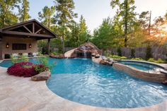 an outdoor swimming pool surrounded by rocks and plants with a waterfall in the middle that leads to a gazebo