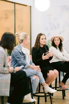 three women sitting in chairs talking to each other