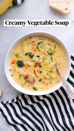 a bowl of soup with broccoli, carrots and bread on the side