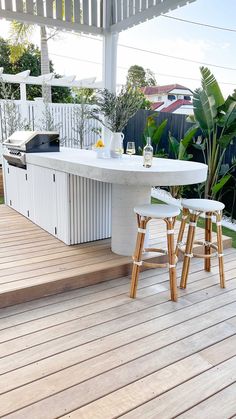 an outdoor kitchen with bar stools next to it