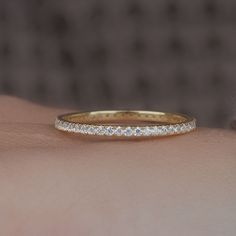 a woman's hand with a yellow gold wedding band on her left wrist and the ring has five small white diamonds in it