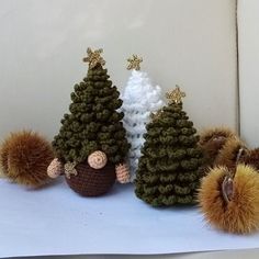 three knitted christmas trees with pom - poms on them sitting next to each other