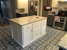 a large kitchen with an island in the middle and stainless steel appliances on both sides