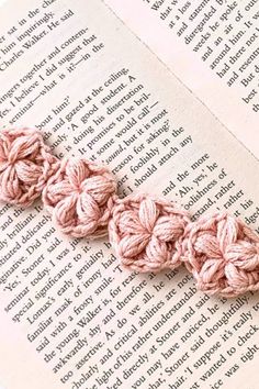 the crochet is laying on top of an open book and it's pink color