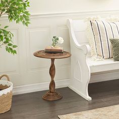 a white bench and table in a room with wood flooring next to a potted plant