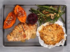 a tray with meat, green beans and sweet potato wedges next to mashed potatoes