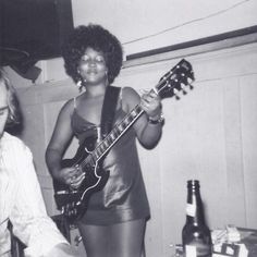 a woman holding a guitar while standing next to a man