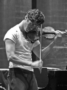 a man playing the violin in front of a piano