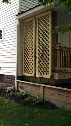 a house with a wooden deck and trellis on the front door, next to a tree