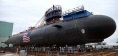 a large black submarine sitting on top of a train track next to a loading dock