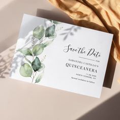 an elegant save the date card with watercolor eucalyptus leaves and gold foil on it