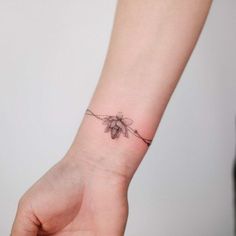 a woman's wrist with a small flower tattoo on the left side of her arm