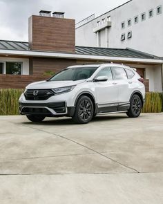 a white honda cr - v parked in front of a house