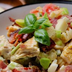 a white plate topped with pasta salad and green leafy garnish on top