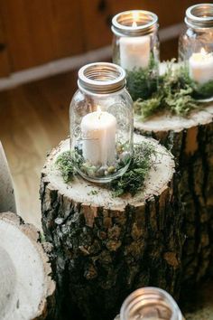 three mason jars filled with candles sitting on top of a tree stump