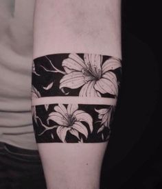 a black and white flower tattoo on the left arm, with two bands around it