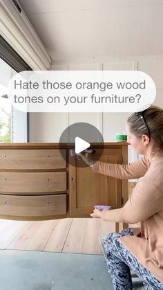 a woman sitting on the floor with a wooden dresser in front of her