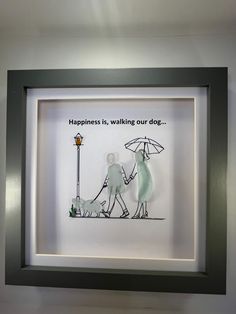 a shadow frame with a drawing of two people holding an umbrella and the words happiness is walking our dog