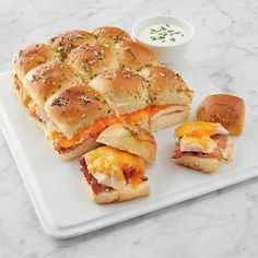 several sandwiches on a white plate with dipping sauce