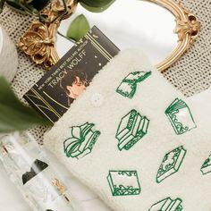 a white towel with green designs on it next to a gold frame and some plants