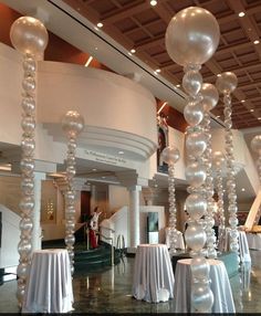 a large room filled with tables covered in white tablecloths and balloons hanging from the ceiling